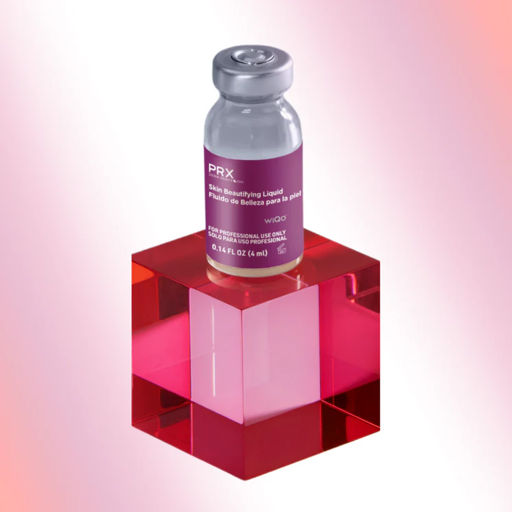 A glass vial of PRX Derm Perfexion Skin Beautifying Liquid by WiQo, sitting on top of a translucent pink acrylic cube against a gradient pink and white background.
