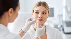 Dermal Filler Consultation at Simple Radiance Medspa - SimpleRadianceMedSpa - SimpleRadianceMedSpa A facial balancing expert wearing a white coat and gloves examines the face of a patient in a white robe during a dermal filler consultation in Austin, Texas.